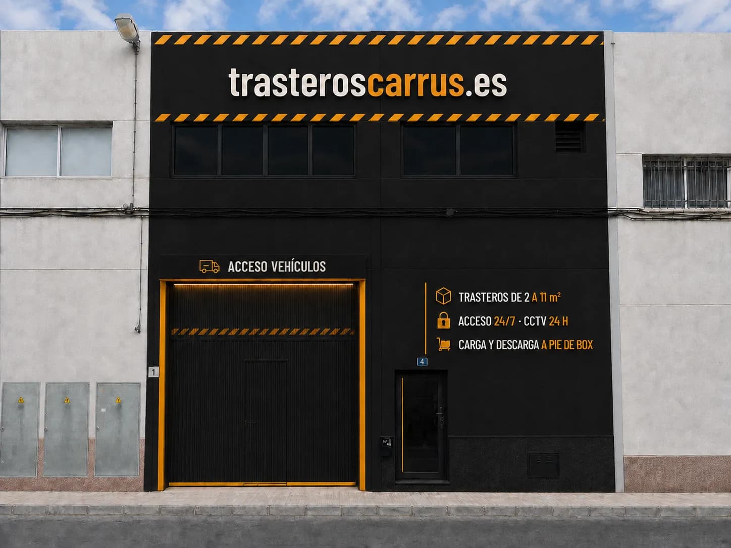 Fachada de la nave de Trasteros Carrús en Calle Requena 4: rotulación con el portón de acceso para vehículos y los servicios del centro